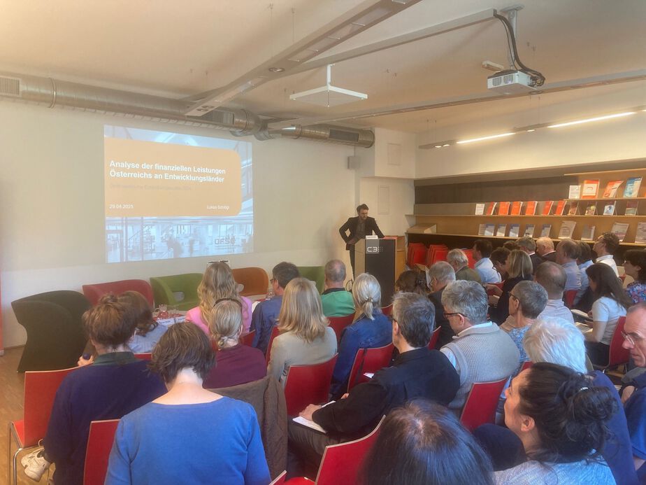 Präsentation: "Österreichische Entwicklungspoliitk 2024" mit Lukas Schlögl Foto von der Präsentation mit dem Vortragenden, der Powerpoint-Präsentation und dem Publikum